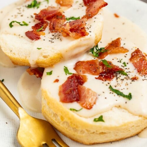 bacon gravy on biscuits with bacon pieces and chopped parsley on top