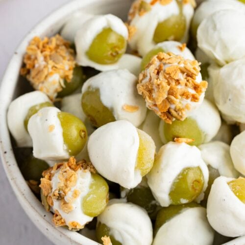 Frozen yogurt-covered grapes with granola in a bowl