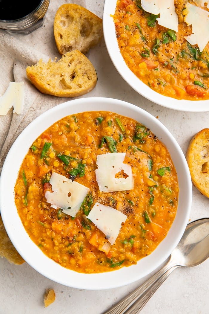 Overhead, zoomed out photo of Instant Pot lentil soup in white bowls, surrounded by crusty bread