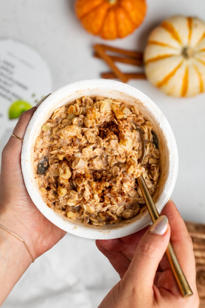 Two hands holding an oat bowl with spoon