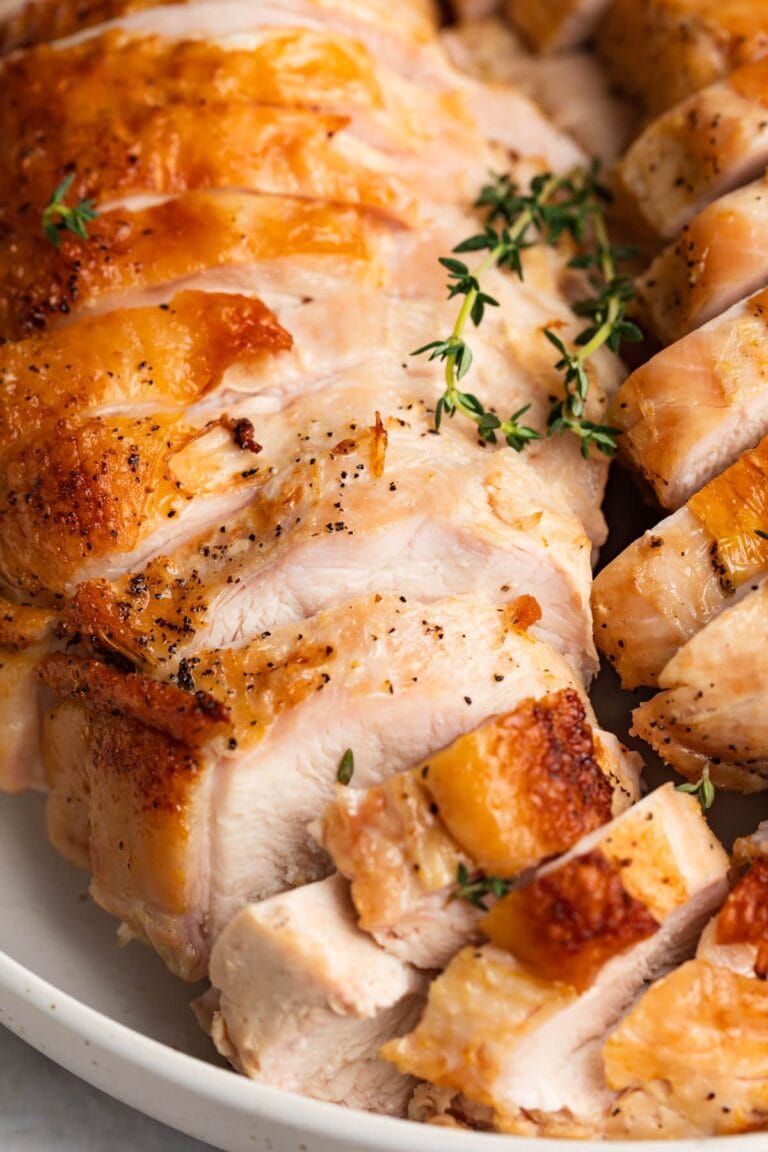 close-up image of sliced sous vide turkey breast with fresh thyme on top