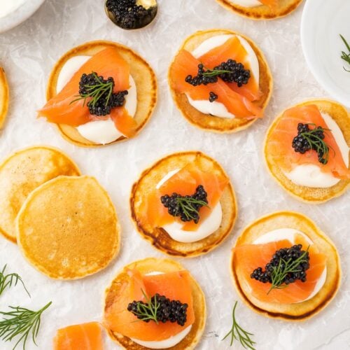 Blini, some topped with salmon and caviar, spread out on a table