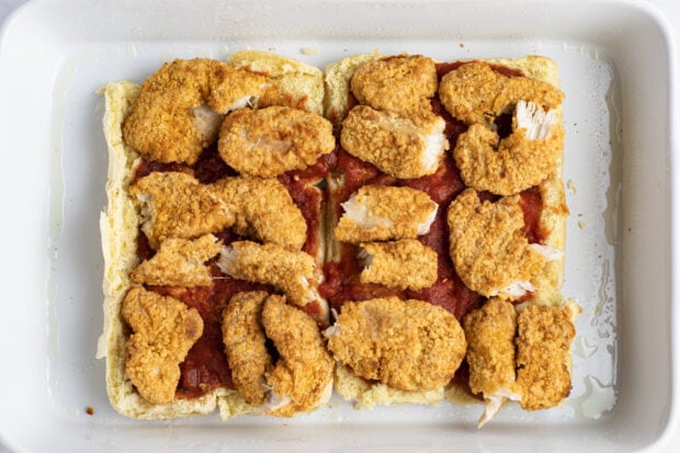 Crispy chicken strips on top of sweet rolls and marinara sauce