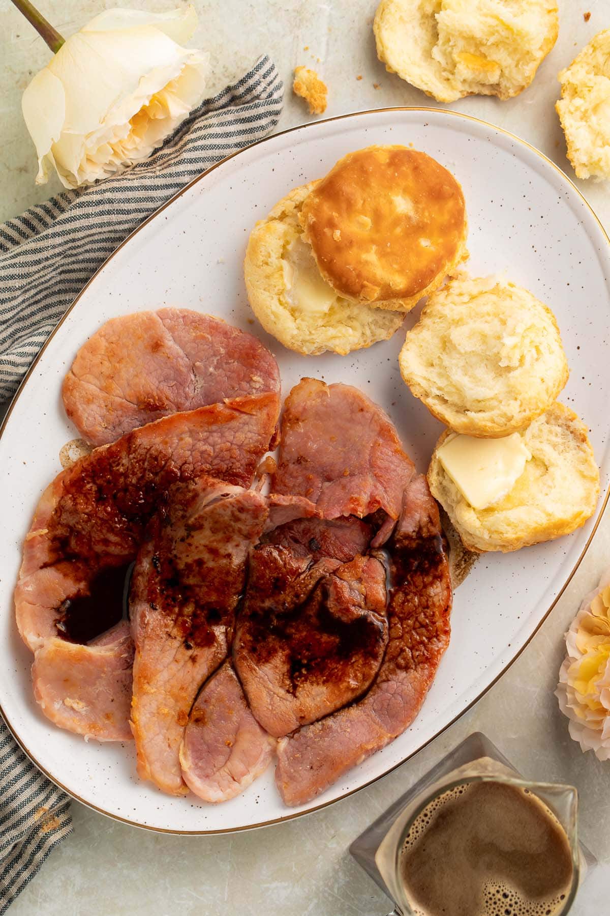 Red eye gravy poured over country ham on an oval platter with fluffy biscuits.