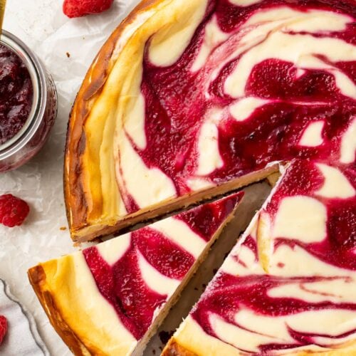 A slice of keto white chocolate raspberry cheesecake slightly removed from the rest of the cheesecake