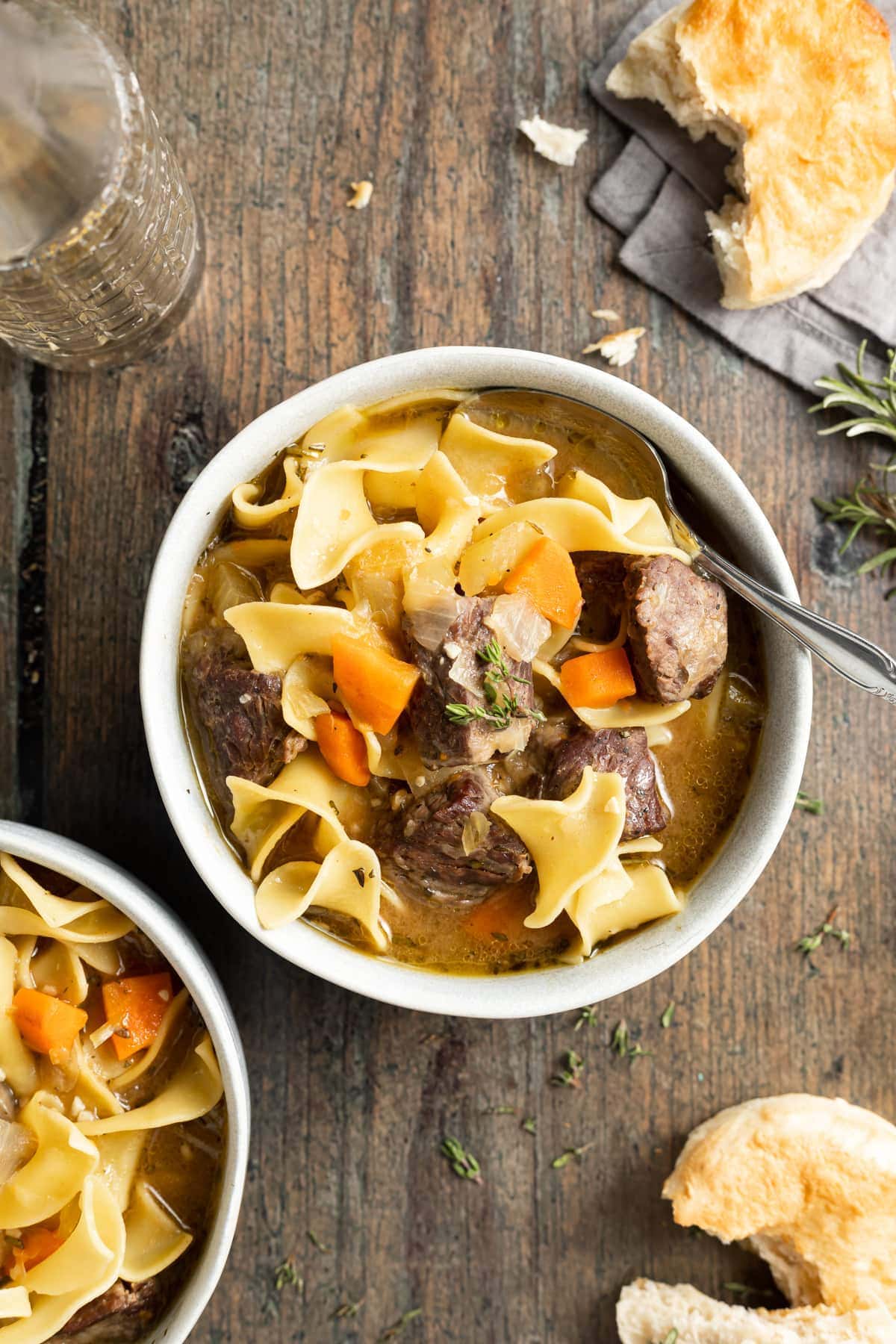 overhead image of beef noodle soup in two bowl with a spoon