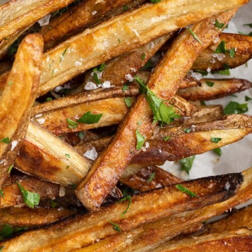 closeup image of parmesan truffle fries with fresh parsley on top