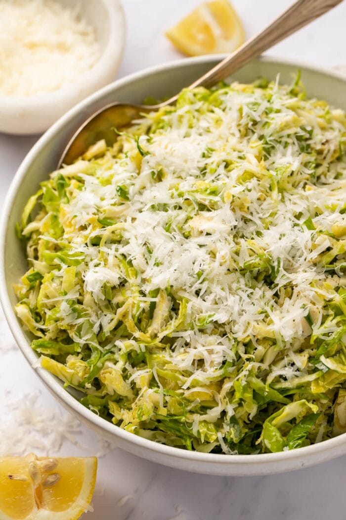 Angled side view of a bowl of shaved Brussels sprouts salad with lemon and parmesan