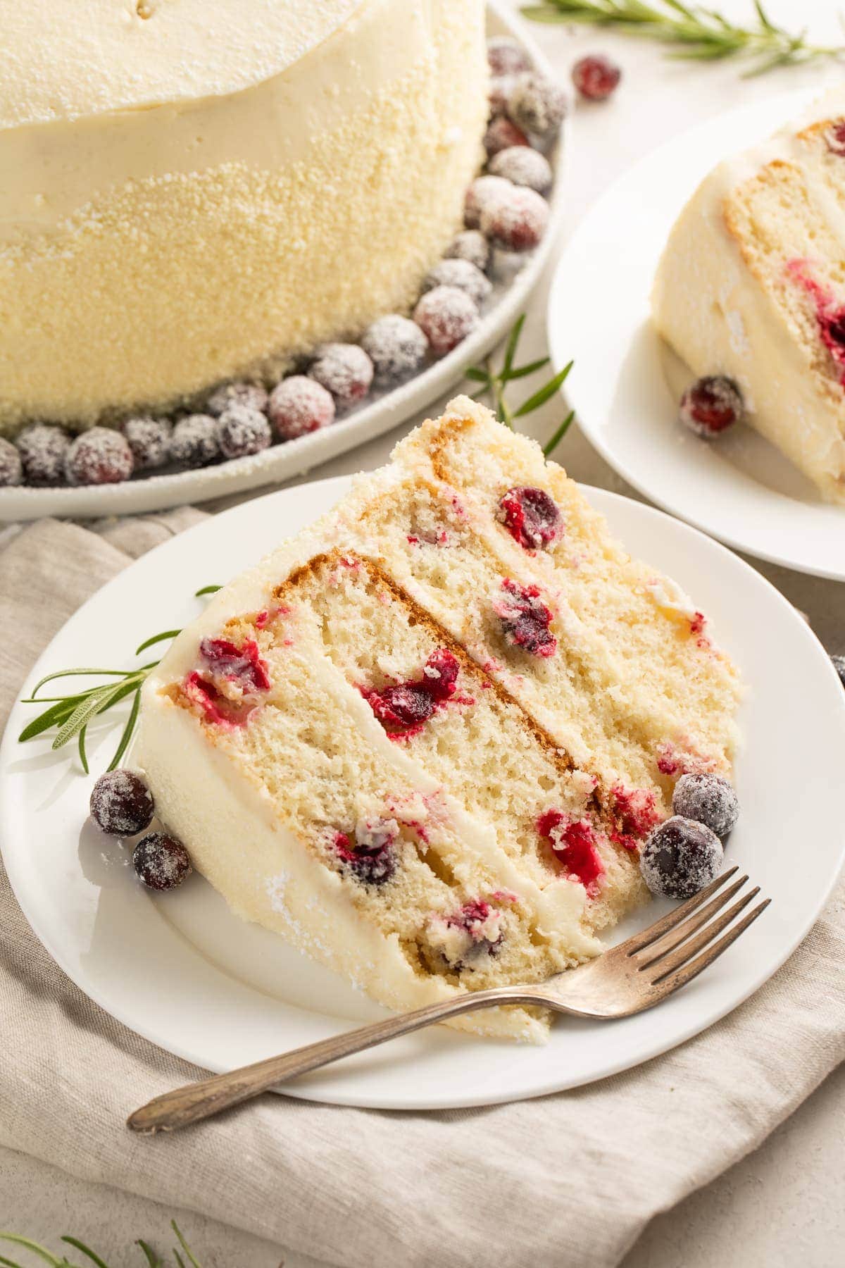 A slice of cranberry white chocolate cake on a white plate with a fork.