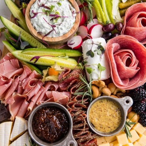 Close up view of keto charcuterie board with salami roses, dips, bacon jam, prosciutto, radishes, and cheeses