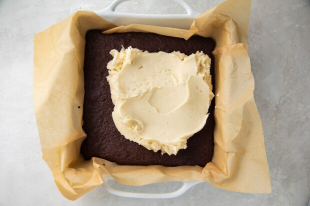 Buttercream on top of keto peppermint brownies in baking dish lined with parchment paper