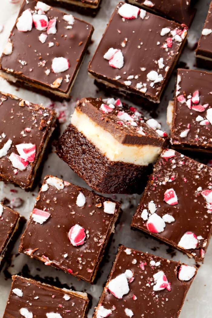 Overhead view of keto peppermint layer brownies on parchment paper, with the center brownie on its side so you can see the layers