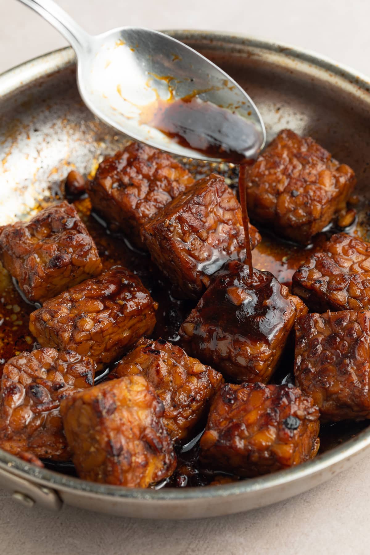 spooning marinade over cooked tempeh