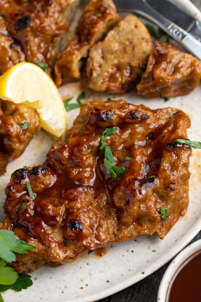 seitan grilled chicken on a plate with fresh parsley and a lemon wedge