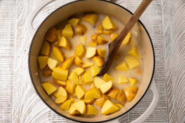 Uncooked potatoes and vegetable broth in dutch oven