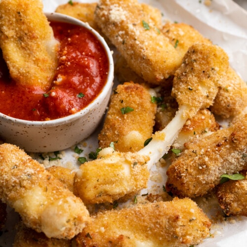 close-up image of air fryer mozzarella sticks on a plate with marinara sauce