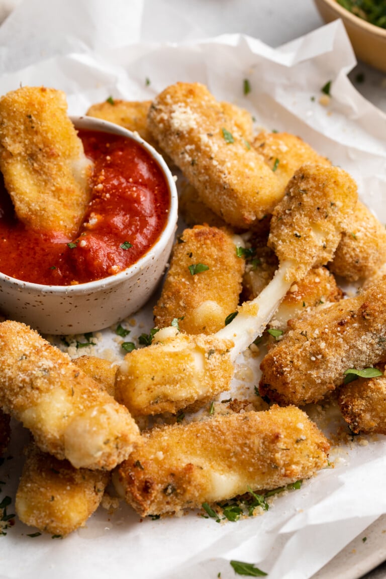 close-up image of air fryer mozzarella sticks on a plate with marinara sauce