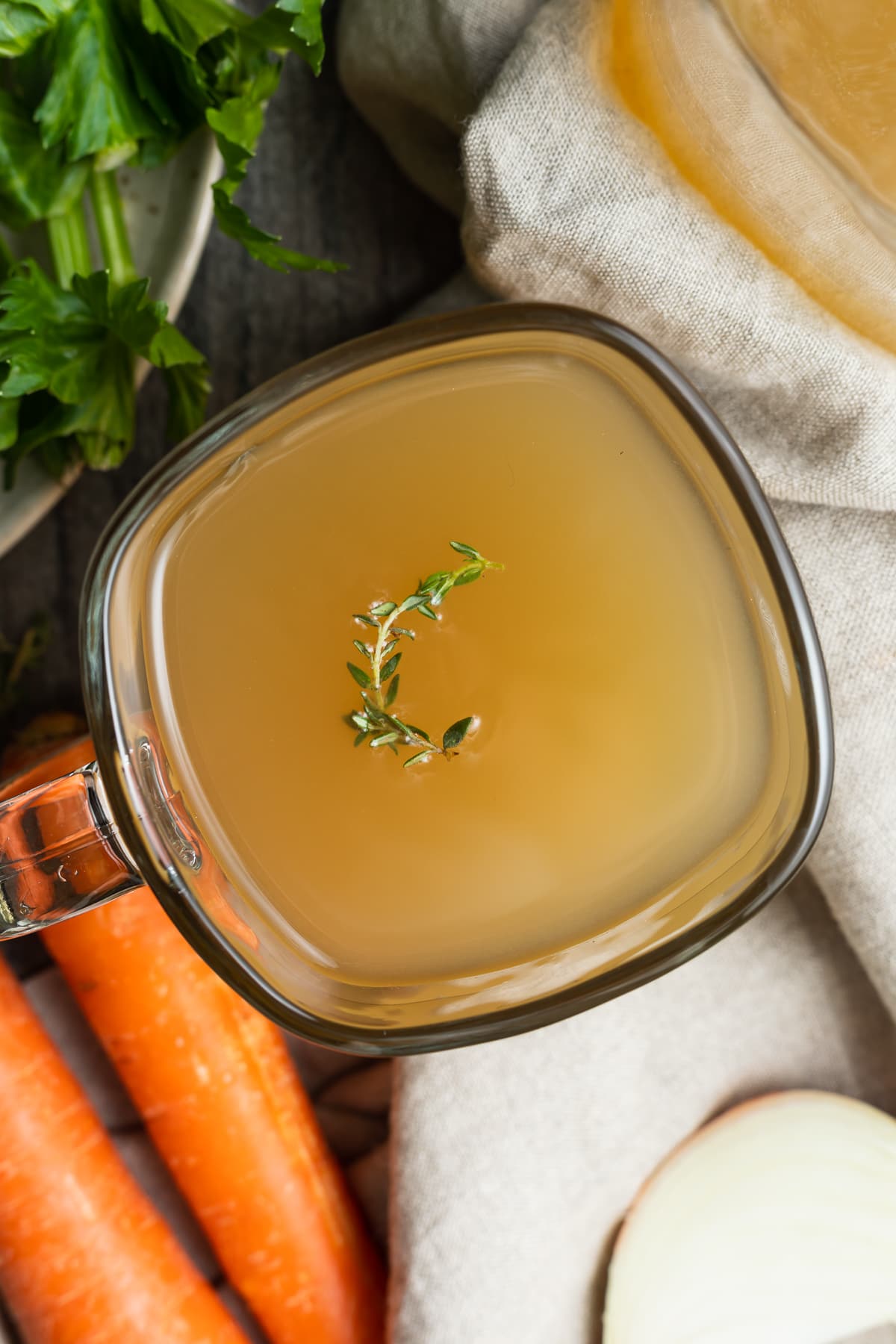 crockpot bone broth in a mug with fresh thyme on top.