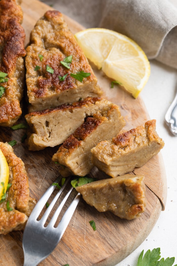 seitan chicken sliced on a cutting board with fresh parsley on top