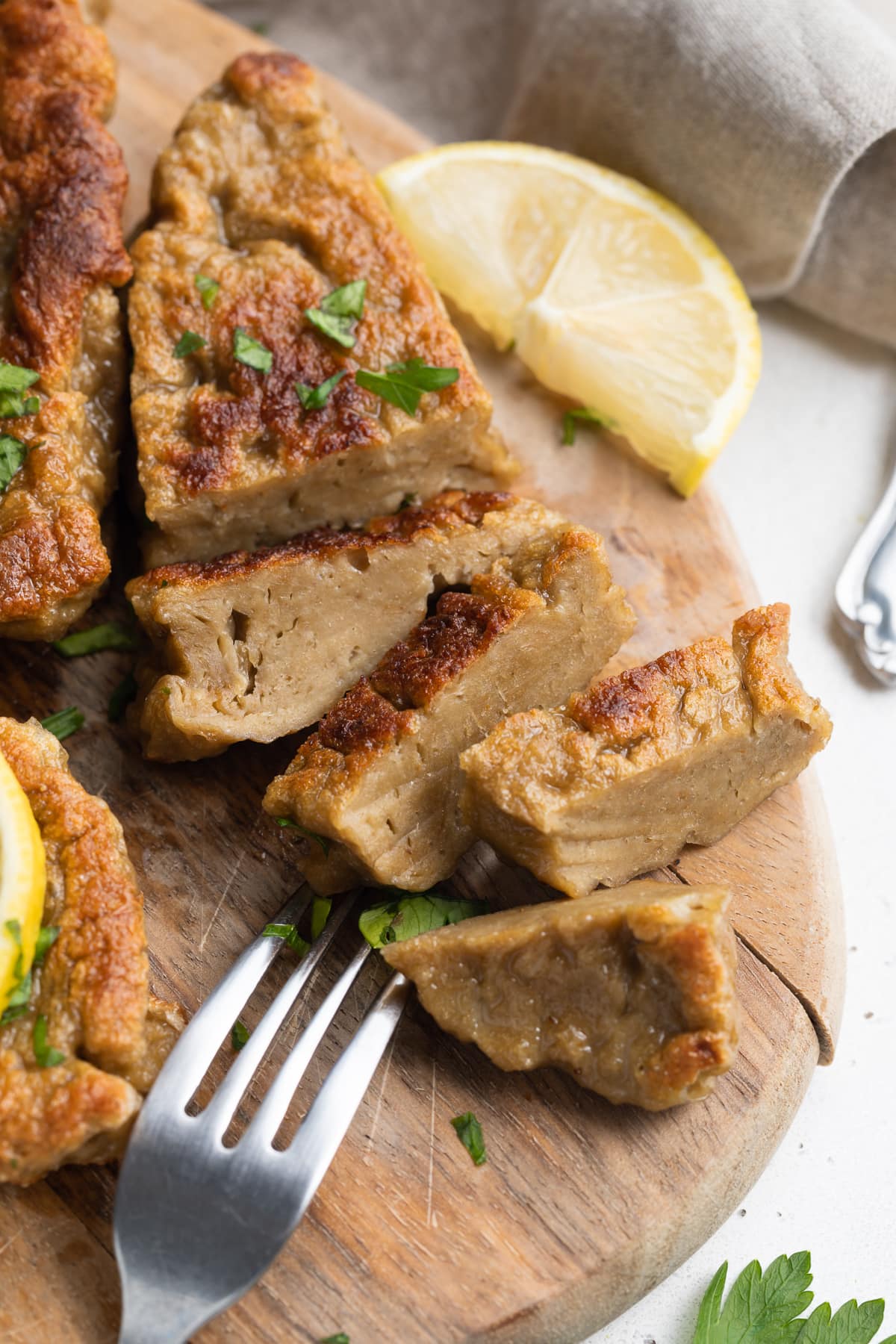 seitan chicken sliced on a cutting board with fresh parsley on top