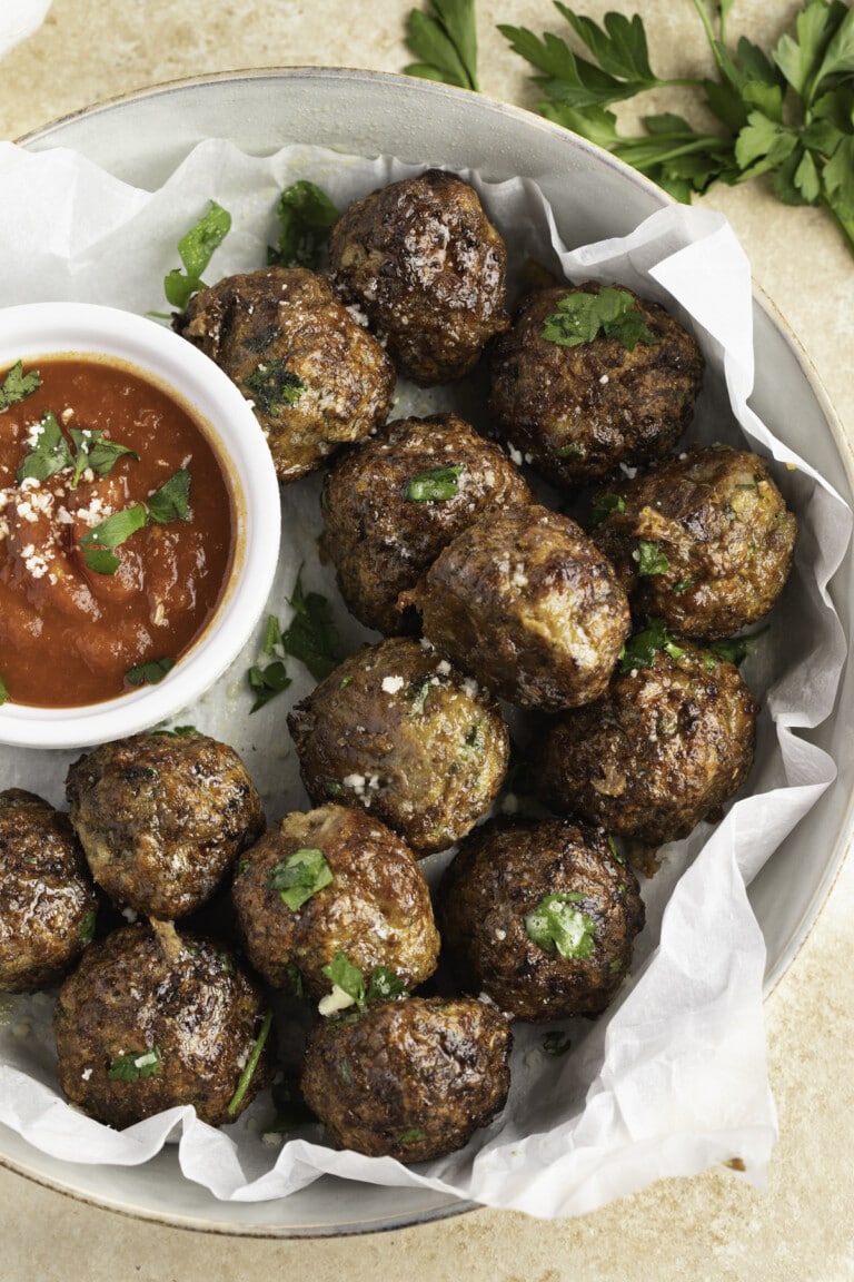 Air fryer meatballs on a plate with a ramekin of marinara sauce