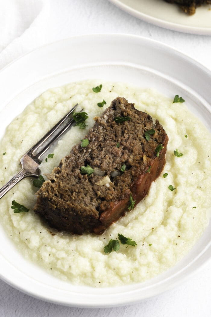 Overhead angled view of a slice of paleo meatloaf on a bed of mashed potatoes