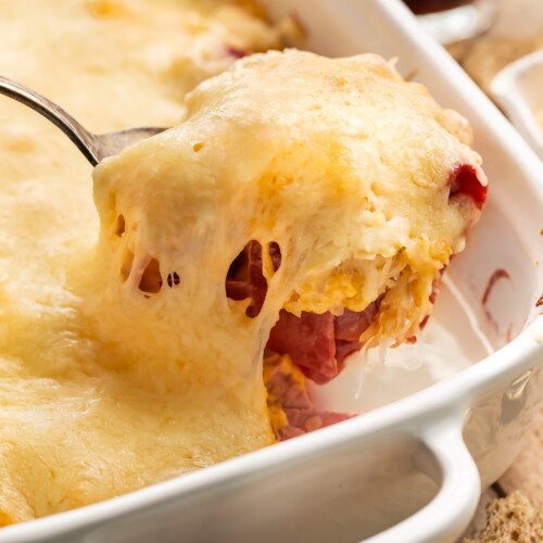 A scoop of reuben casserole being lifted out of a casserole dish.