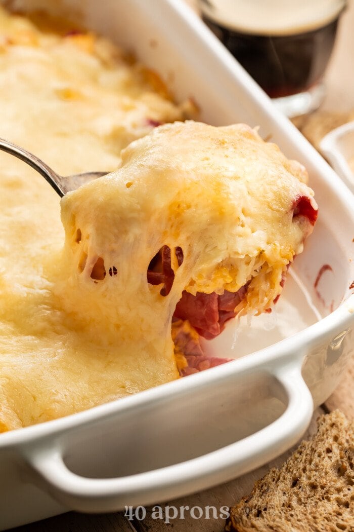 A scoop of reuben casserole being lifted out of a casserole dish.