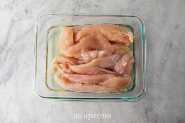 Chicken tenders in pickle juice in a glass baking dish