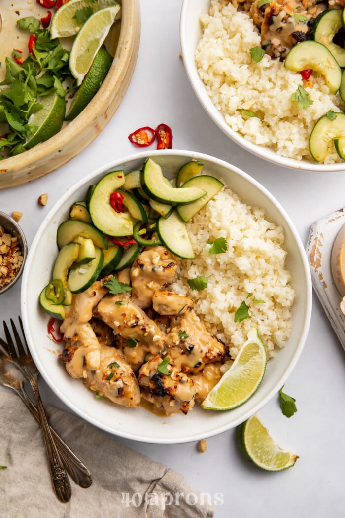 Overhead view of bowls of Whole30 peanut chicken on a light countertop