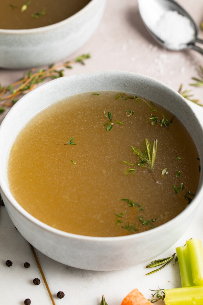 two bowls of bone broth with fresh herbs on top