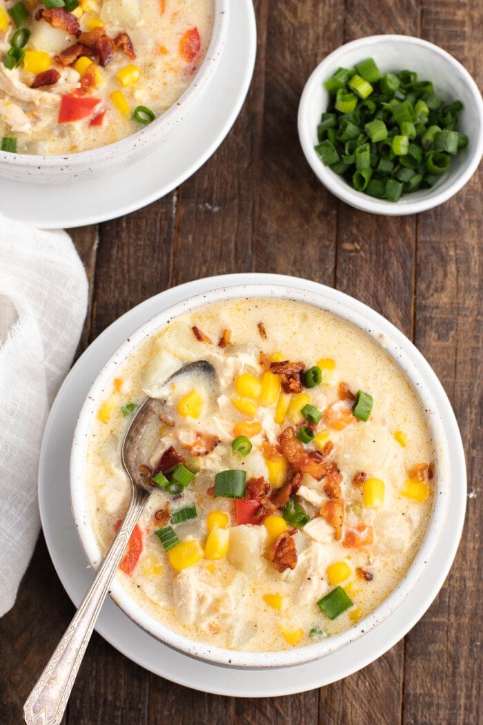 Overhead view of a bowl of chicken corn chowder on a wooden table.