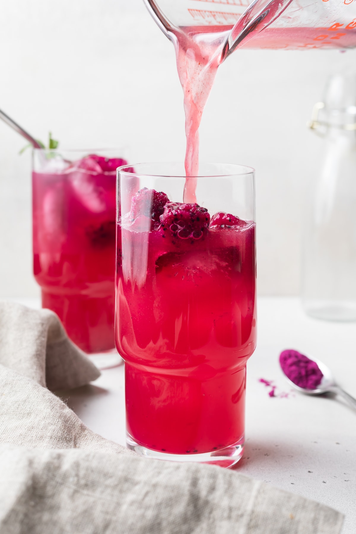 mango dragon fruit refresher being poured into a glass with ice