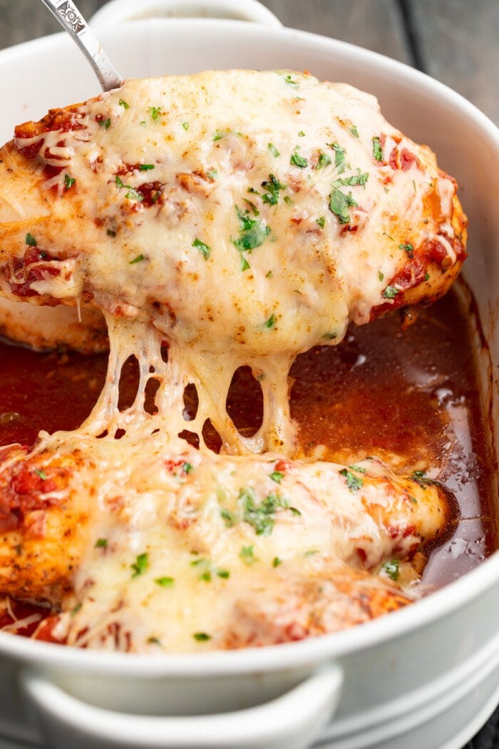 cheesy salsa chicken being lifted out of a baking dish