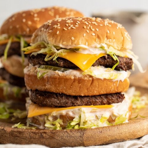 A stack of keto big macs on a wooden cutting board.