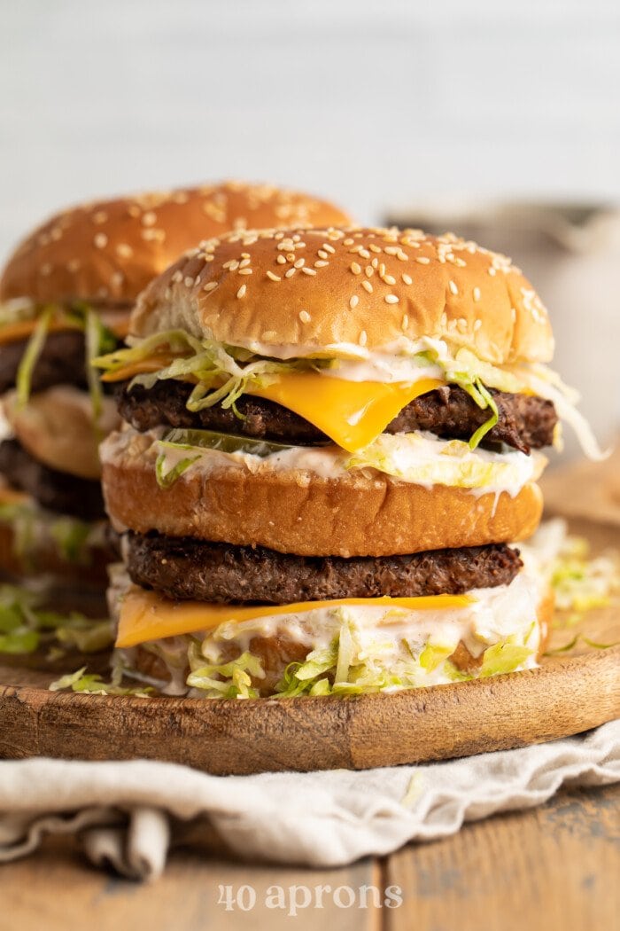 A stack of keto big macs on a wooden cutting board. 