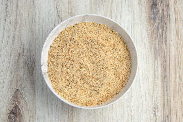 Keto breading mixture in a shallow bowl on a light neutral countertop.