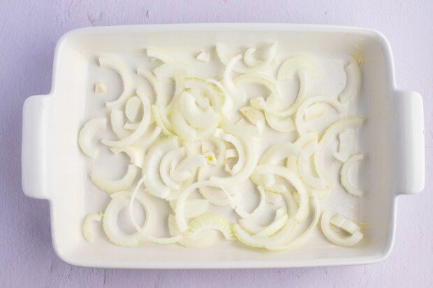 Onion slices lining bottom of a greased 9x13 baking dish.