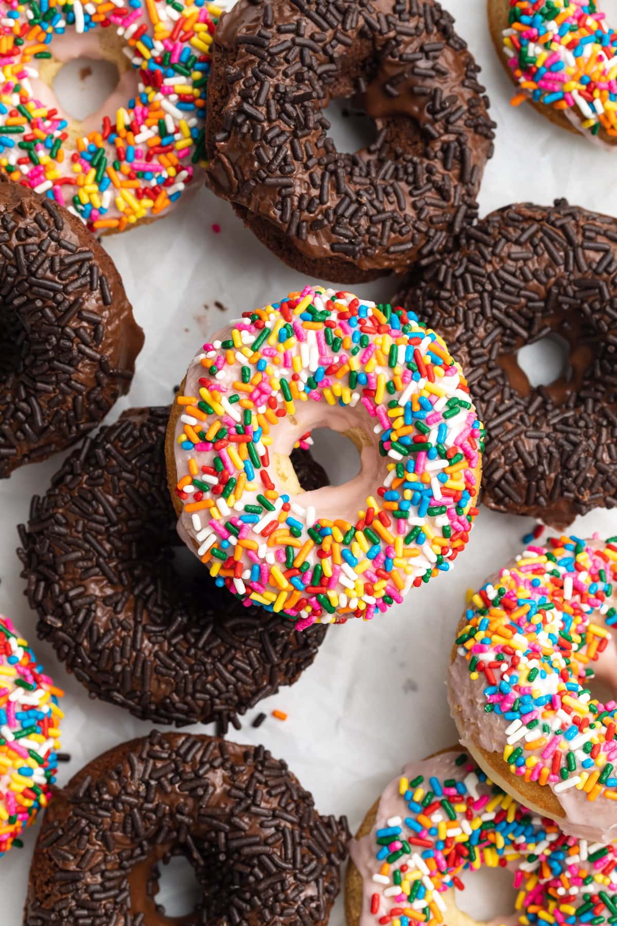 Overhead view of a mix of chocolate and vanilla gluten-free sprinkled donuts.