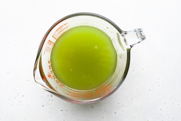 Overhead view of a glass pitcher containing lime green kiwi starfruit refresher liquid.