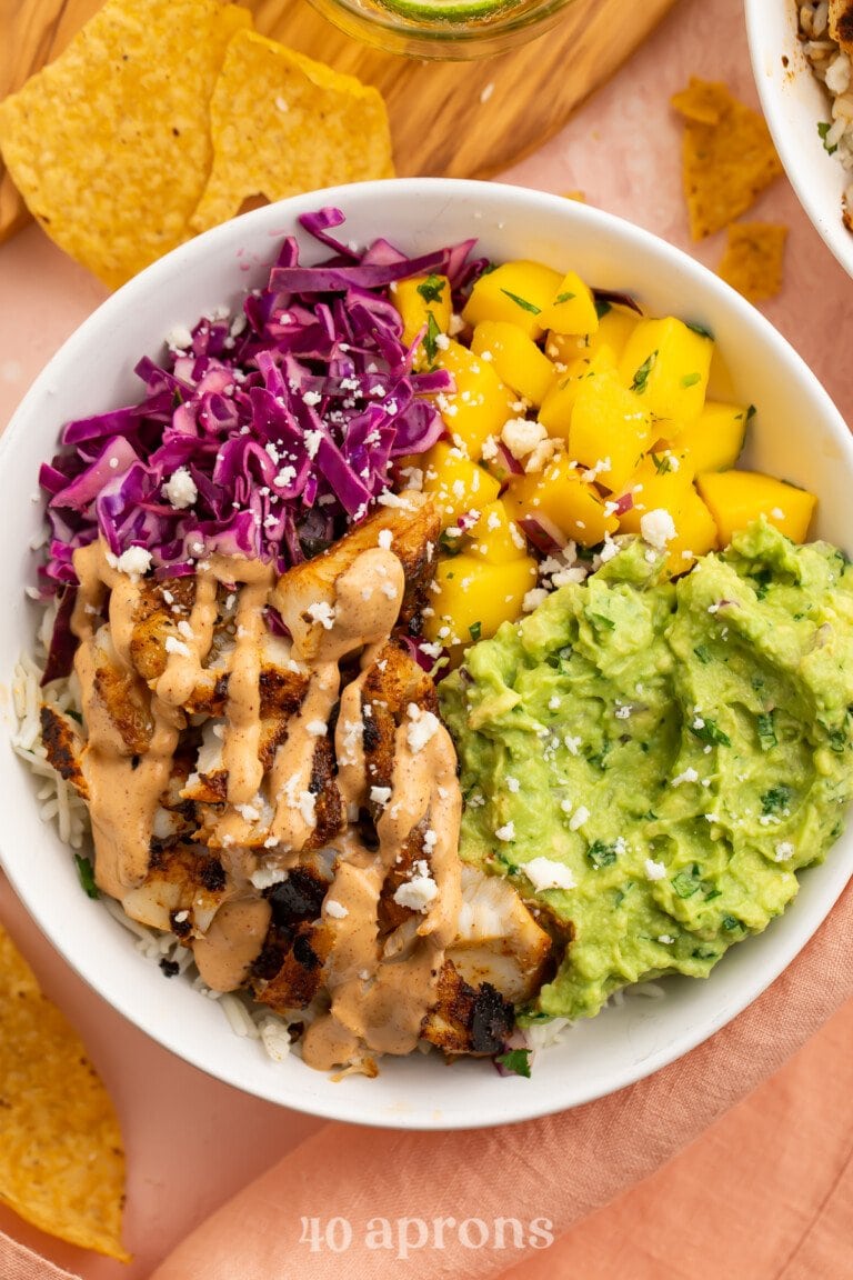 Overhead view of a fish taco bowl with mango salsa and red cabbage slaw.