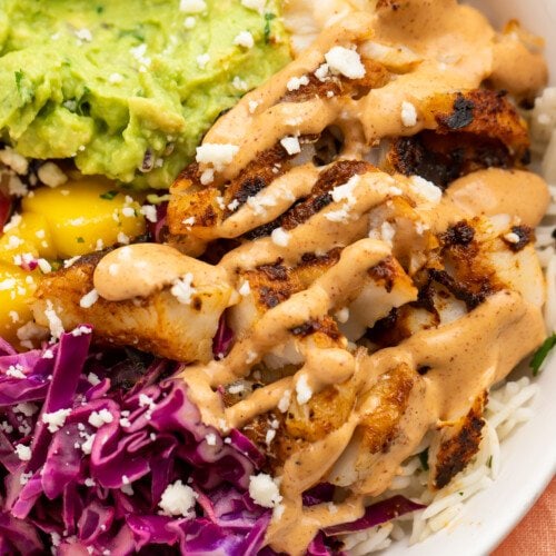 Closeup view of blackened fish taco bowls with gauc and red cabbage slaw.