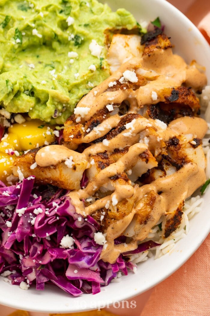 Closeup view of blackened fish taco bowls with gauc and red cabbage slaw.