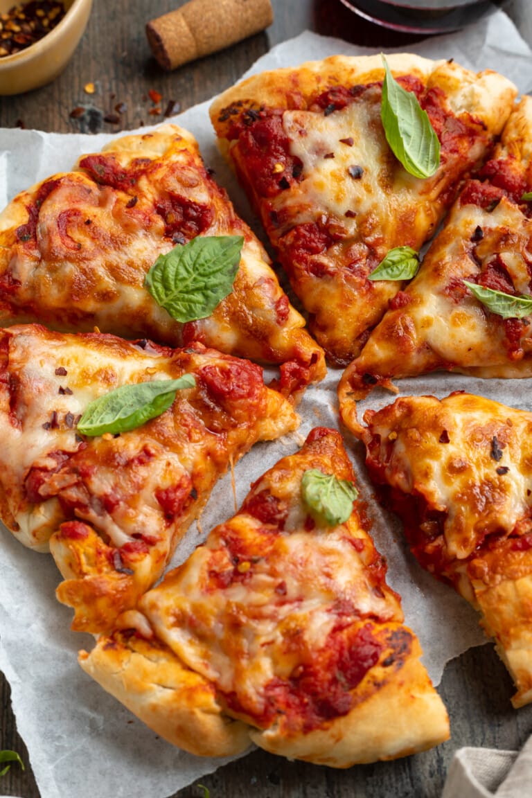 Close-up, angled view of soft and fluffy air fryer pizza on a white plate.