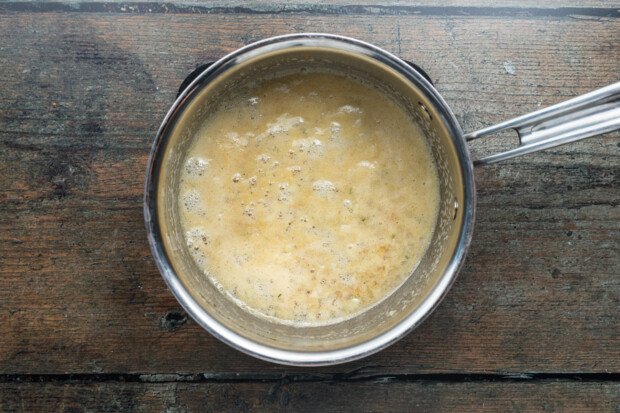 Overhead view of a small saucepan with herb-butter sauce for bacon-wrapped scallops.