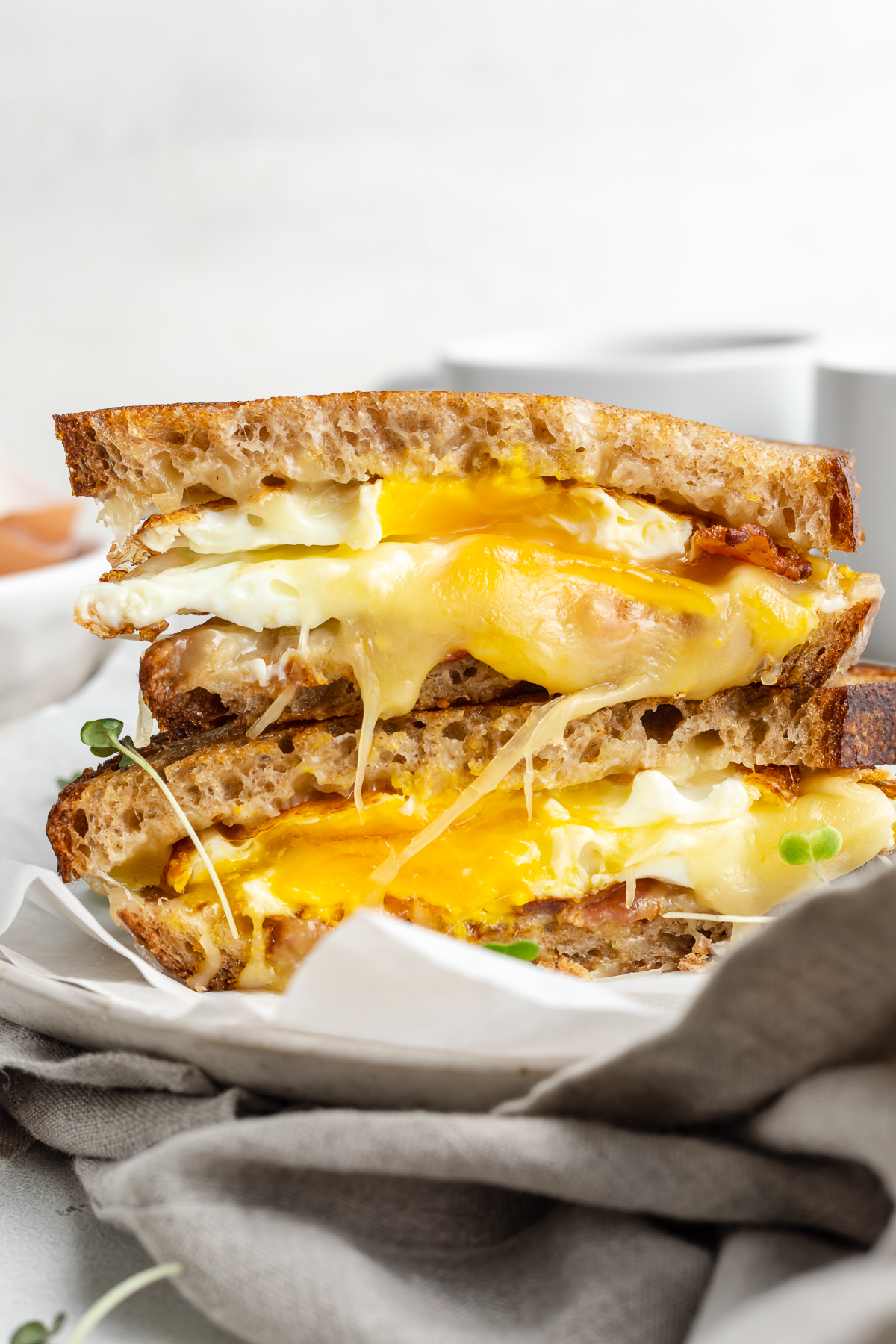 Side view of a fried egg sandwich cut in half, with one half stacked on top of the other.