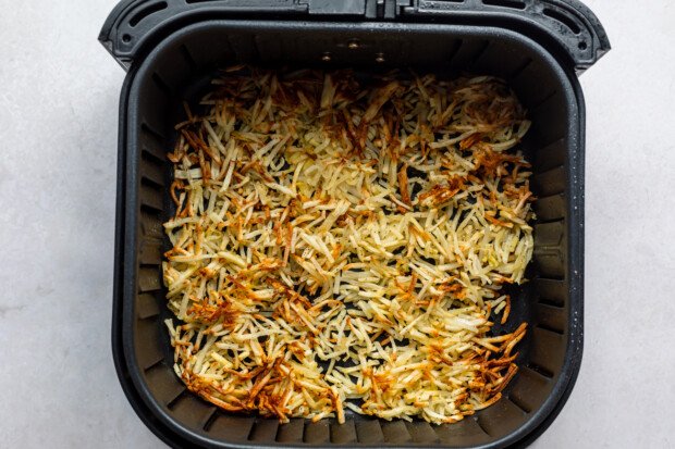 Overhead view of air fryer hashbrowns in an air fryer basket.