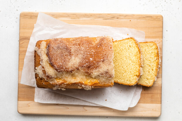 Overhead view of gluten free lemon drizzle cake on a wooden cutting board lined with parchment paper.