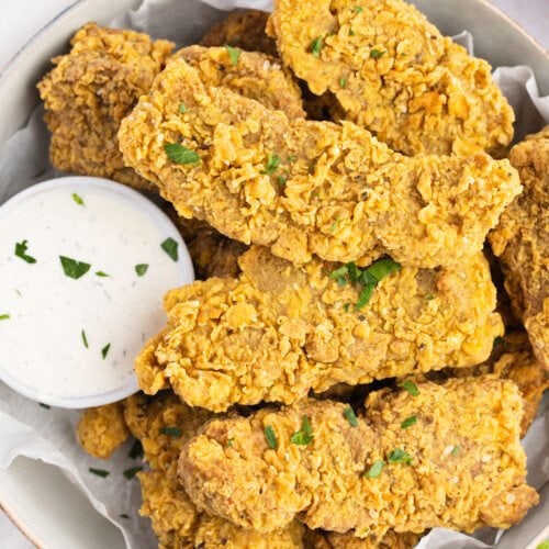 Overhead view of a bowl of vegan seitan fried "chicken" with a small ramekin of vegan ranch dressing.