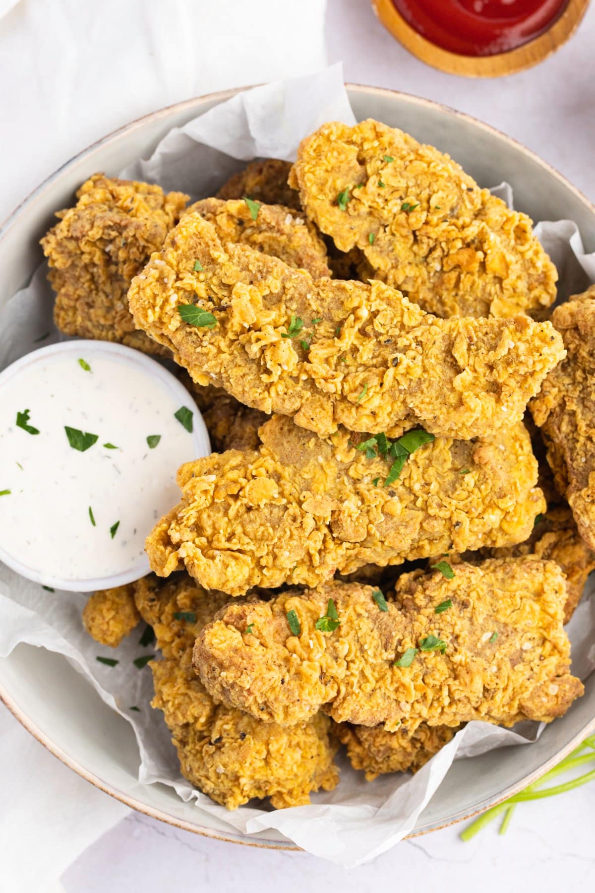 Overhead view of a bowl of vegan seitan fried "chicken" with a small ramekin of vegan ranch dressing.